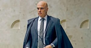 ministro Alexandre de Moraes andando, sério, em pé, olhando para o lado