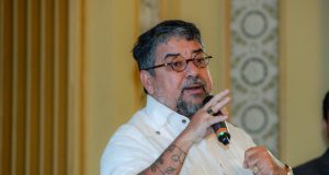 prefeito de Maricá, Washington Quaquá, de roupa social branca, falando em microfone, sério, sem olhar para a câmera