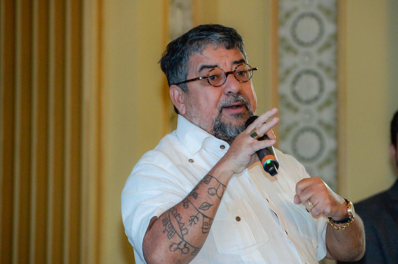 prefeito de Maricá, Washington Quaquá, de roupa social branca, falando em microfone, sério, sem olhar para a câmera