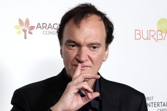 O cineasta Quentin Tarantino, com expressão pensativa e dedo na boca