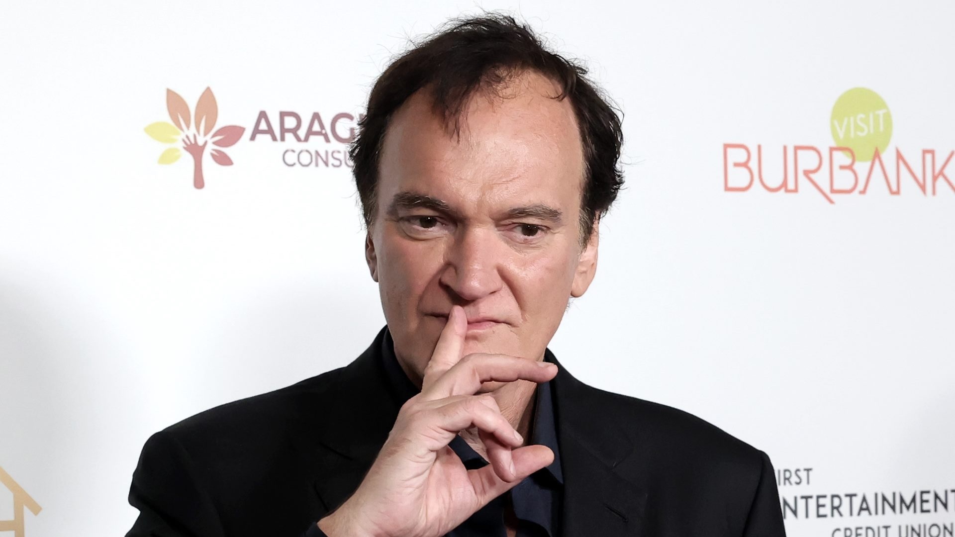 O cineasta Quentin Tarantino, com expressão pensativa e dedo na boca