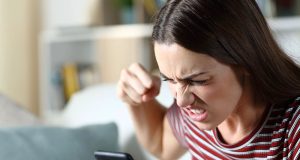 Mulher de cabelo solto e camiseta listrada, gritando com cara de raiva pro celular