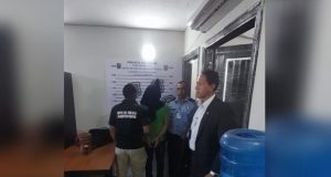 O ex-diretor-geral da Polícia Rodoviária Federal (PRF) Silvinei Vasques encapuzado e algemado no meio de montagem, cercado por agentes