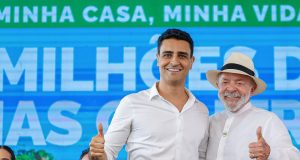 O prefeito de Maceió, João Henrique Caldas, e o presidente Luiz Inácio Lula da Silva (PT), de camisas sociais brancas, sorrindo lado a lado e fazendo joinha para a câmera; Lula de chapéu