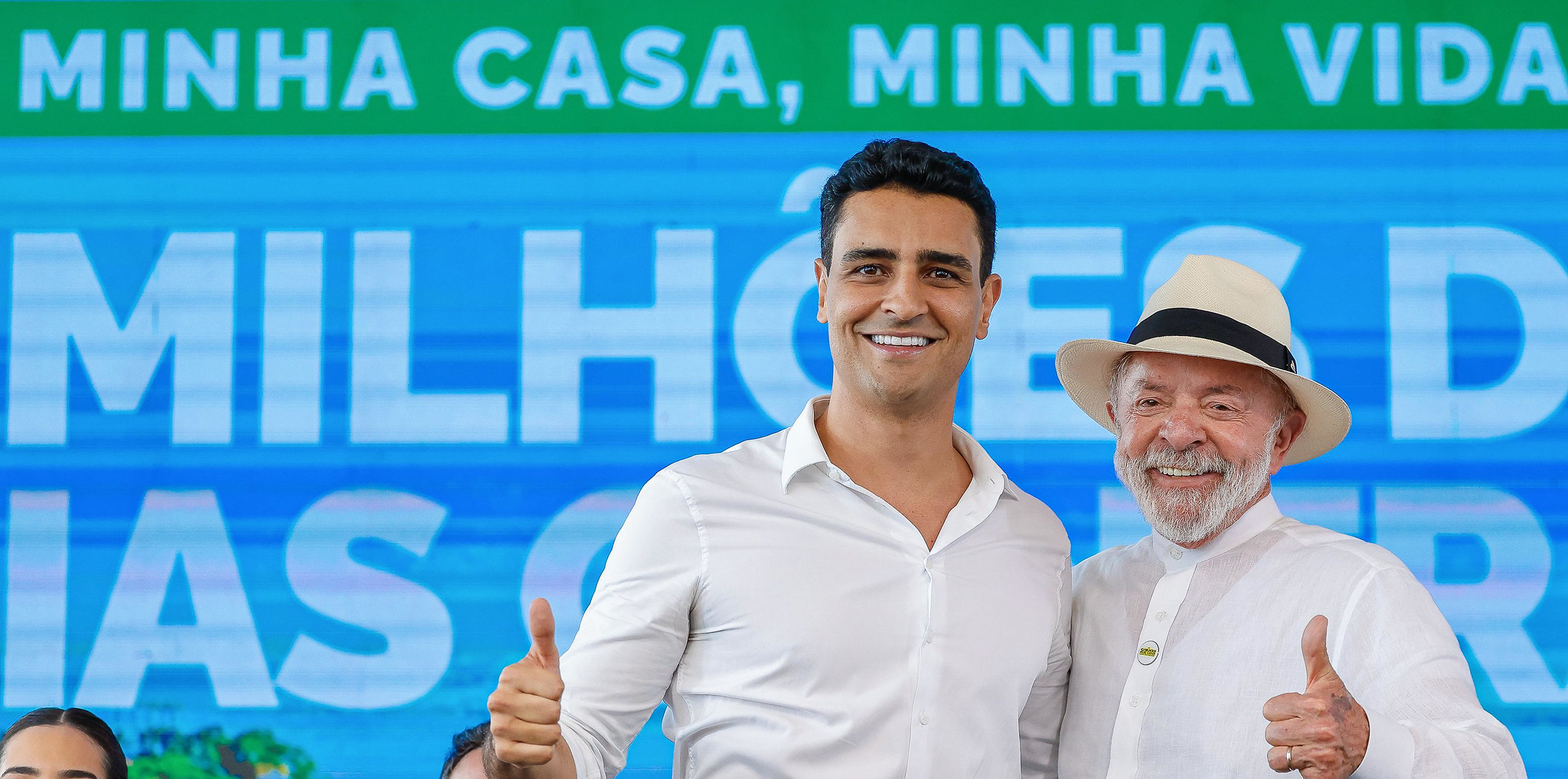 O prefeito de Maceió, João Henrique Caldas, e o presidente Luiz Inácio Lula da Silva (PT), de camisas sociais brancas, sorrindo lado a lado e fazendo joinha para a câmera; Lula de chapéu