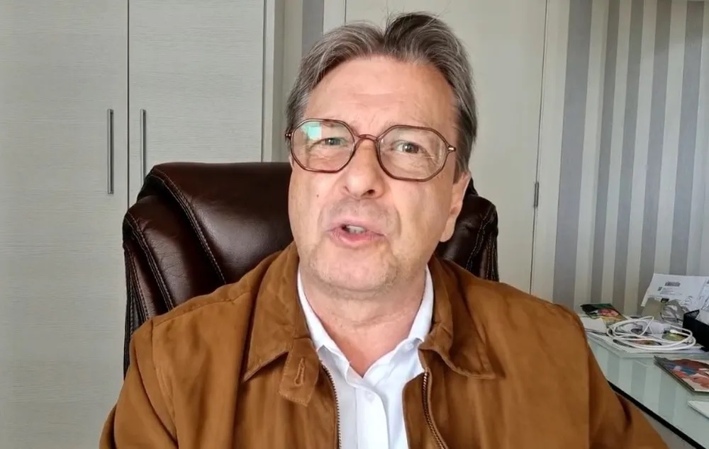 O deputado federal Bibo Nunes de óculos de grau e roupa de frio caramelo e branca falando para a câmera