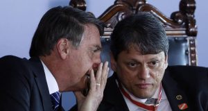 Jair Bolsonaro sentado ao lado de Tarcísio e cochichando no ouvido dele