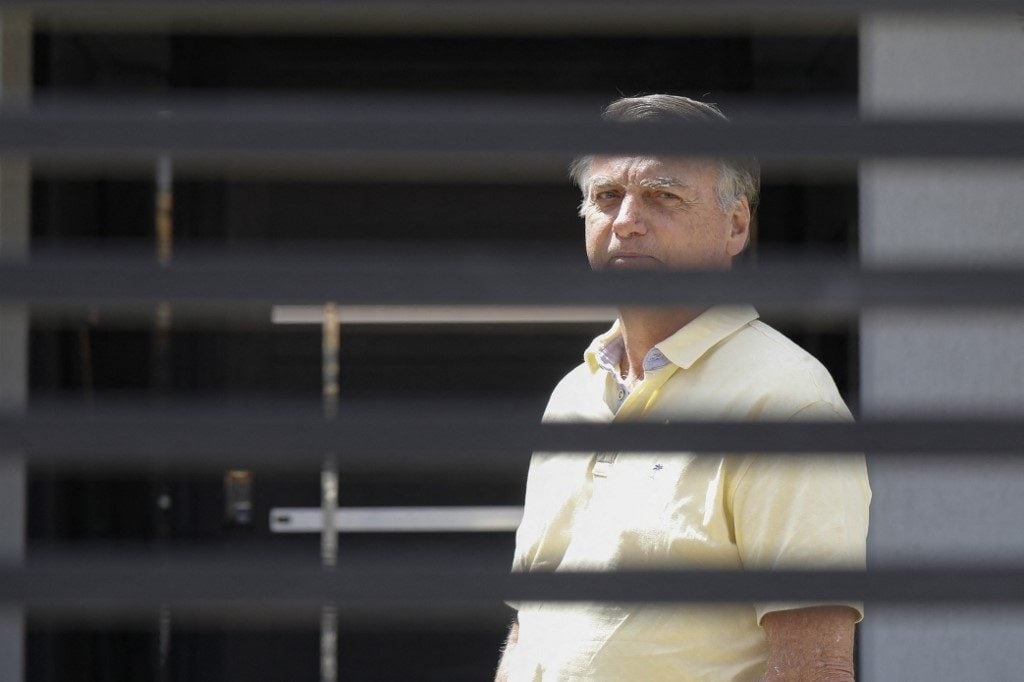 Jair Bolsonaro em prisão domiciliar, de camisa amarela, sério