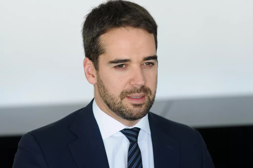 O governador do Rio Grande do Sul, Eduardo Leite, falando, sem olhar para a câmera, de roupa social, sério