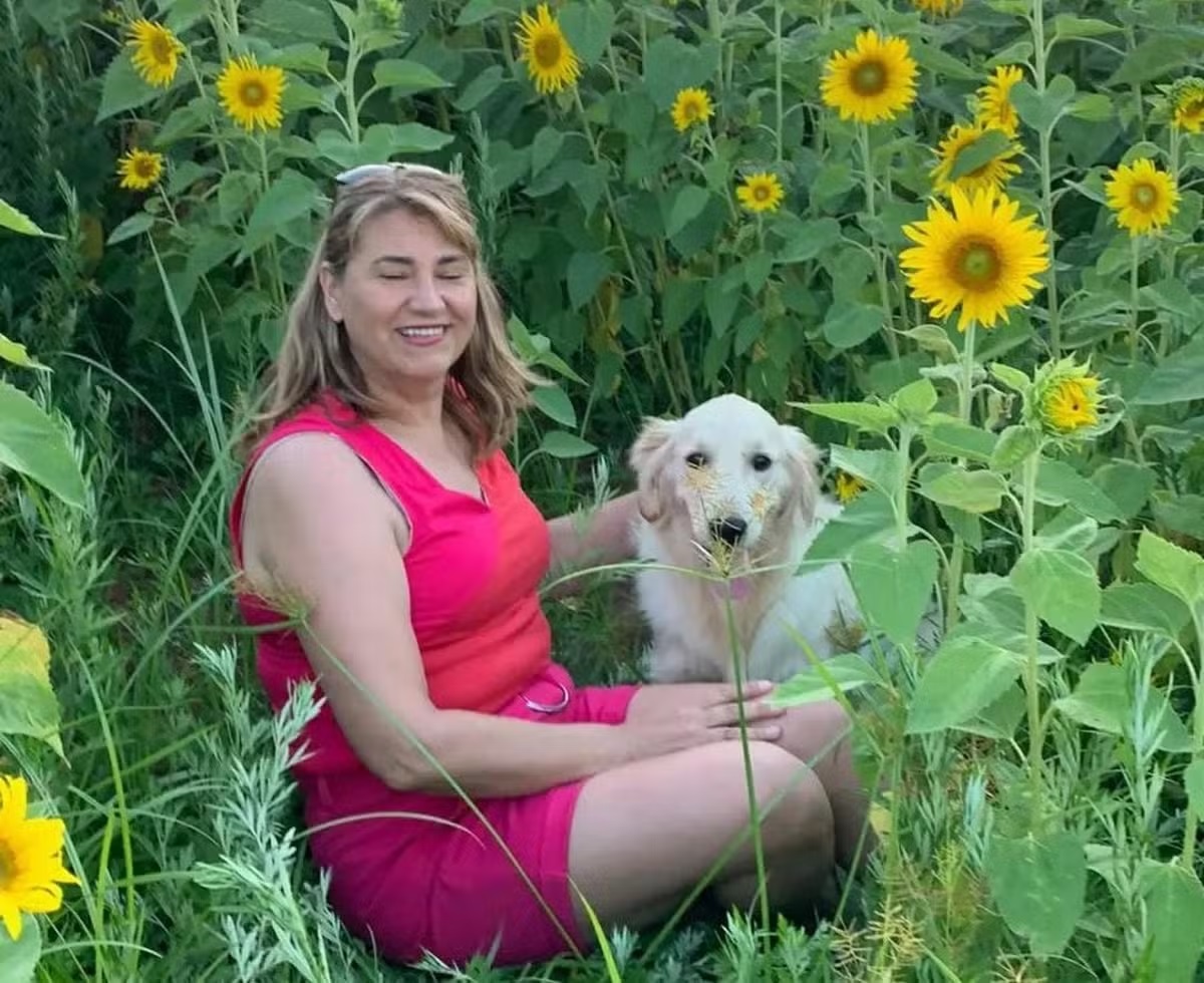 enfermeira Maria Shirlei Piontkievicz sorrindo, com cachorro em campo de girassóis