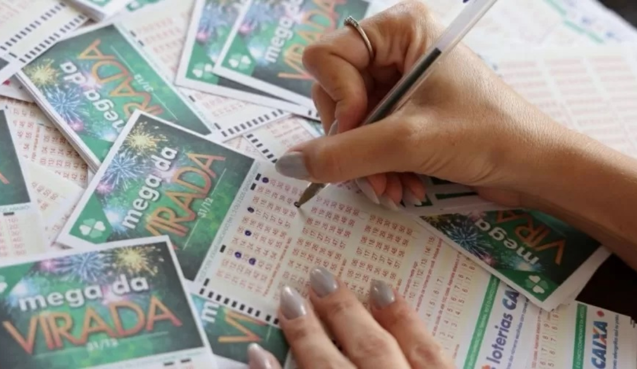 Mãos com unhas pintadas preenchendo talões da Mega da Virada