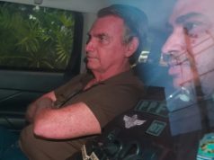 ex-presidente Jair Bolsonaro dentro de carro, sério, sentado, de braços cruzados, de camisa polo marrom