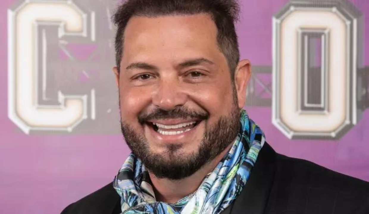 O cantor Conrado sorrindo e olhando para a câmera, em close