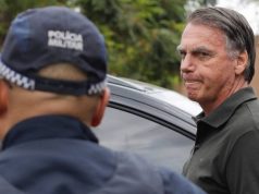 O ex-presidente Jair Bolsonaro (PL) sério, perto de policial, que está de costas
