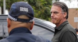 O ex-presidente Jair Bolsonaro (PL) sério, perto de policial, que está de costas