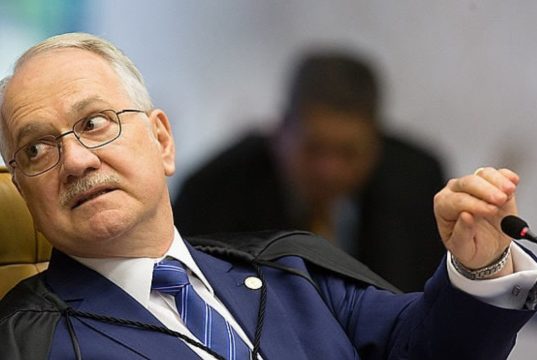 O presidente do Supremo Tribunal Federal, Edson Fachin, sério, segurando microfone, olhando para trás