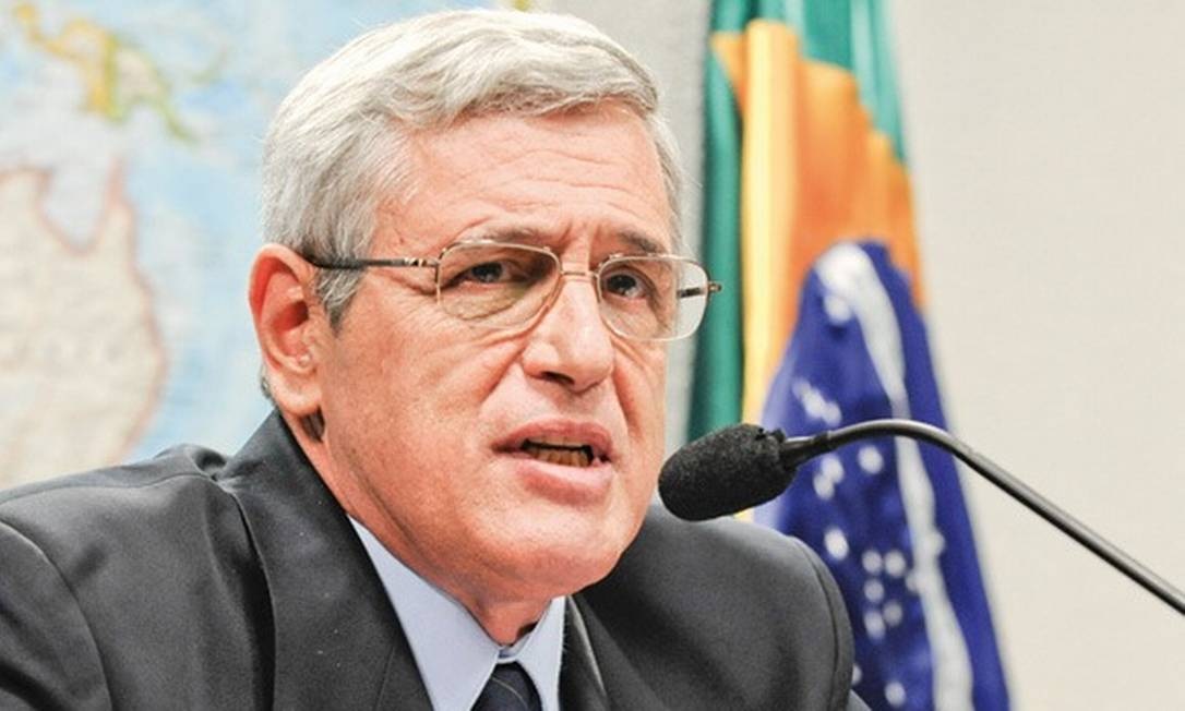 general da reserva Luiz Eduardo Rocha Paiva falando em microfone, sério, com bandeira do Brasil ao fundo