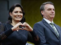 Michelle Bolsonaro ao lado de Jair Bolsonaro, ele sério e ela fazendo coração com as mãos