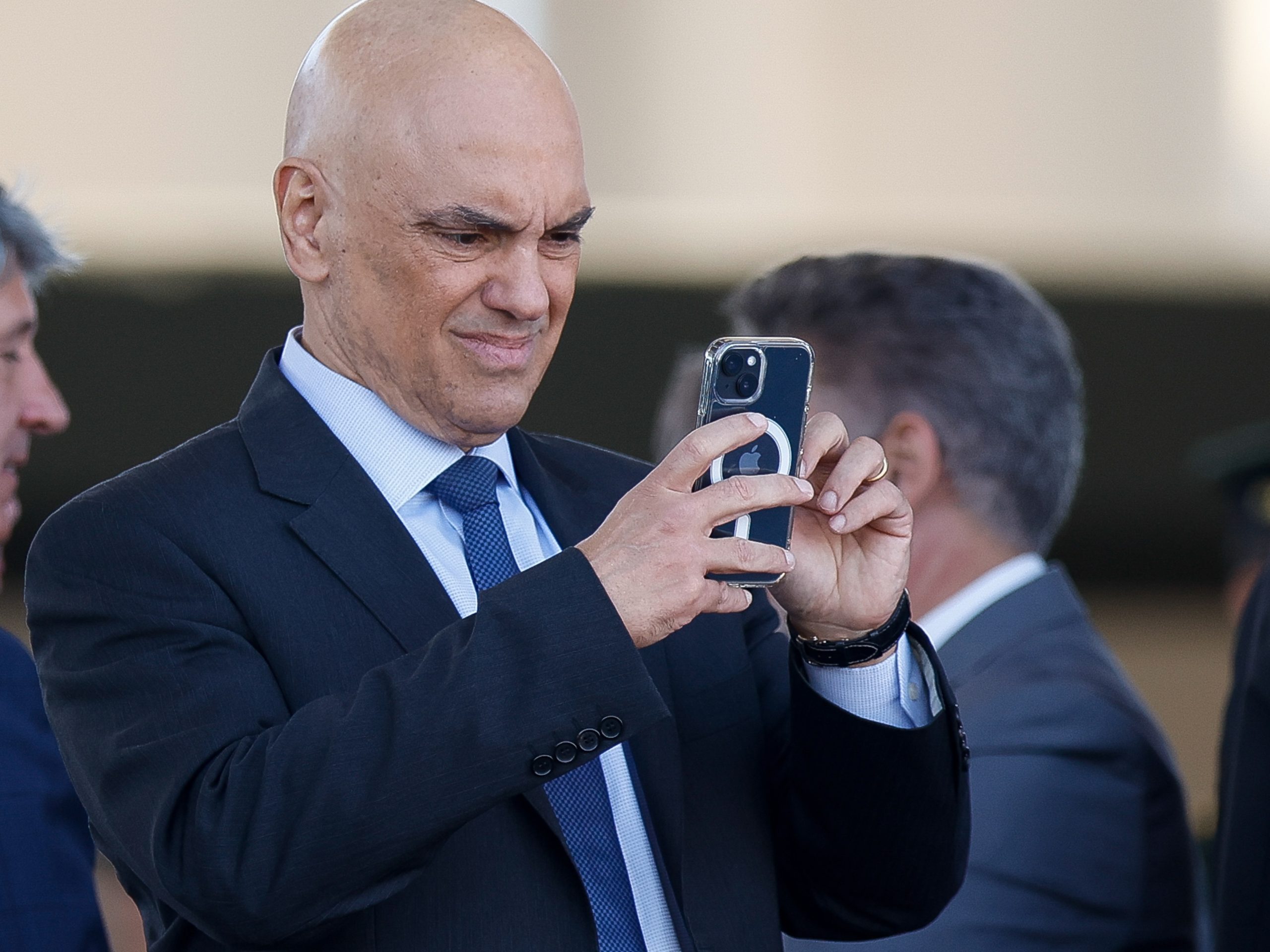 O ministro Alexandre de Moraes, do Supremo Tribunal Federal (STF) segurando celular, sério