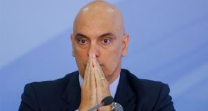 ministro do Supremo Tribunal Federal Alexandre de Moraes sério, com as mãos unidas na frente do rosto, sem olhar para a câmera