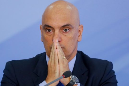 ministro do Supremo Tribunal Federal Alexandre de Moraes sério, com as mãos unidas na frente do rosto, sem olhar para a câmera