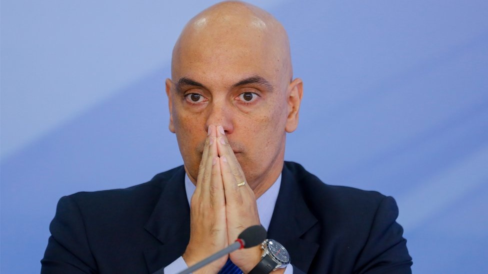 ministro do Supremo Tribunal Federal Alexandre de Moraes sério, com as mãos unidas na frente do rosto, sem olhar para a câmera