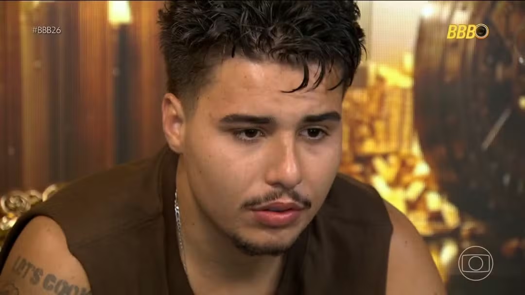 Pedro com expressão triste, de regata marrom, sem olhar para a câmera