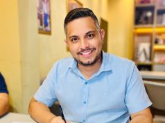 O prefeito de Nossa Senhora do Livramento (MT), Thiago Gonçalo Lunguinho de Almeida (União), de camisa polo azul, sentado, sorrindo e olhando para a câmera