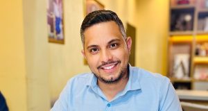 O prefeito de Nossa Senhora do Livramento (MT), Thiago Gonçalo Lunguinho de Almeida (União), de camisa polo azul, sentado, sorrindo e olhando para a câmera