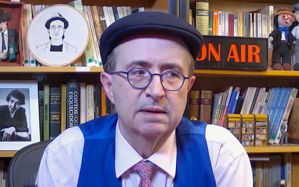 O jornalista Reinaldo Azevedo com expressão pensativa, de óculos de grau e boina, sem olhar para a câmera