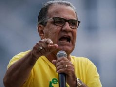 pastor Silas Malafaia de camisa verde e amarela e óculos de grau, falando em microfone e apontando, sério