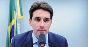 O ministro de Portos e Aeroportos, Silvio Costa Filho, sério, perto de microfone
