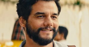 Wagner Moura sorrindo, em close, em cena de O Agente Secreto