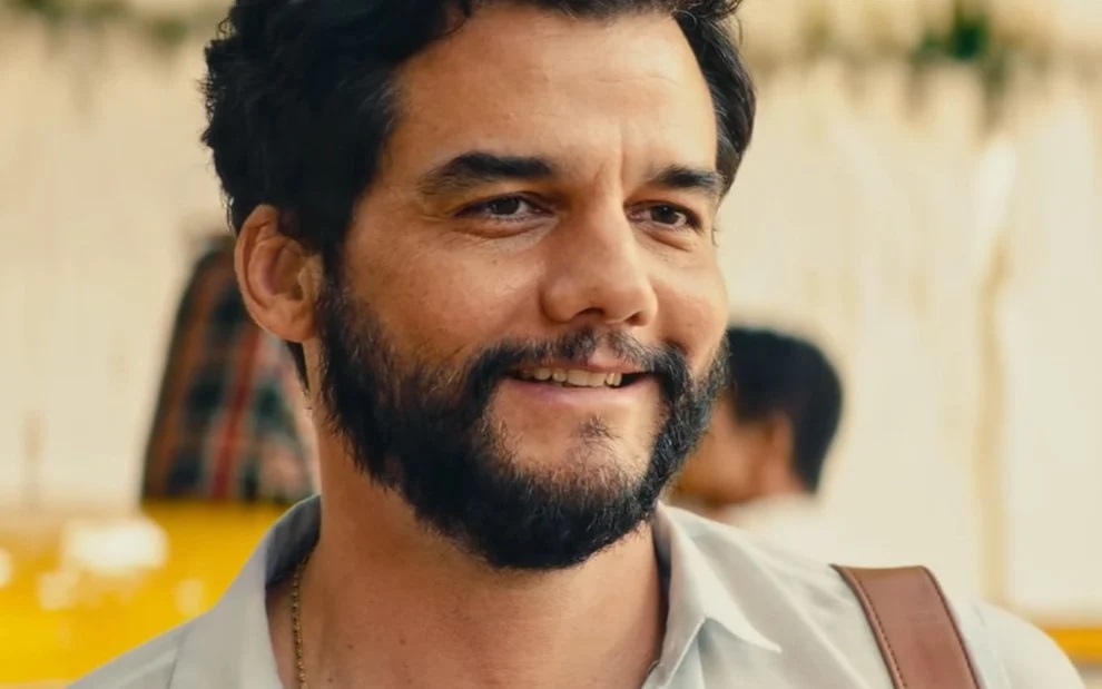 Wagner Moura sorrindo, em close, em cena de O Agente Secreto