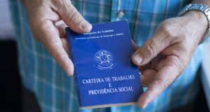 Mãos masculinas segurando carteira de trabalho