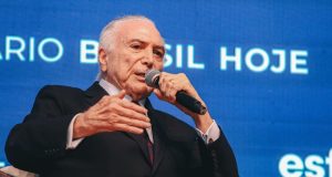 ex-presidente Michel Temer falando em microfone e gesticulando, sério