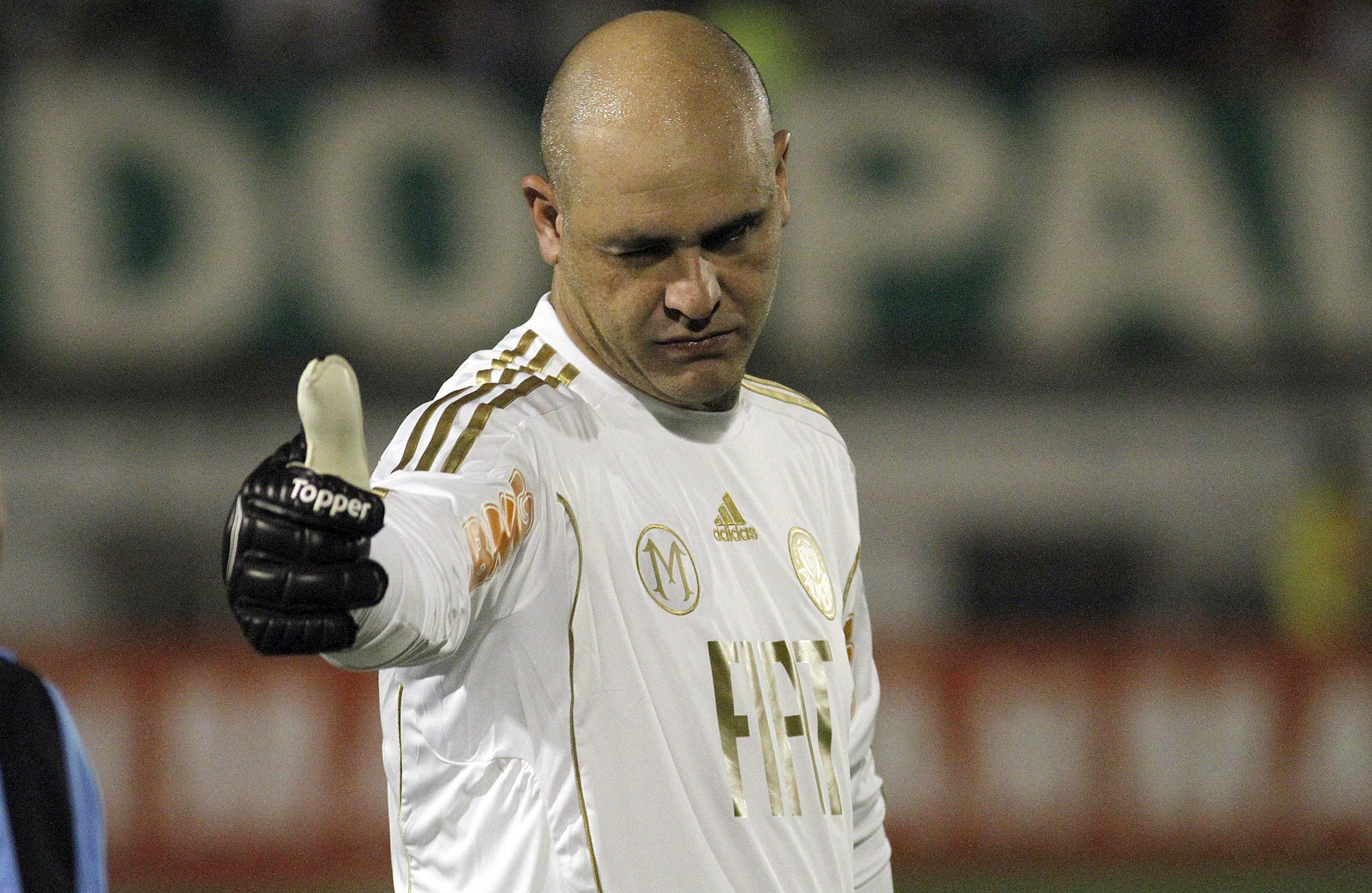 ex-goleiro do Palmeiras fazendo joinha, sério, em campo, de uniforme