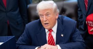 Donald Trump falando, sentado, sério