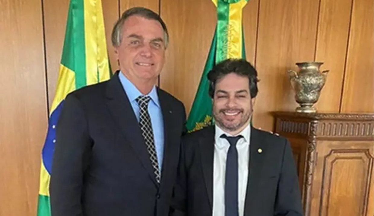 Jair Bolsonaro e Vinicius Gurgel (PL-AP) em pé, lado a lado, de roupa social, sorrindo para a câmera