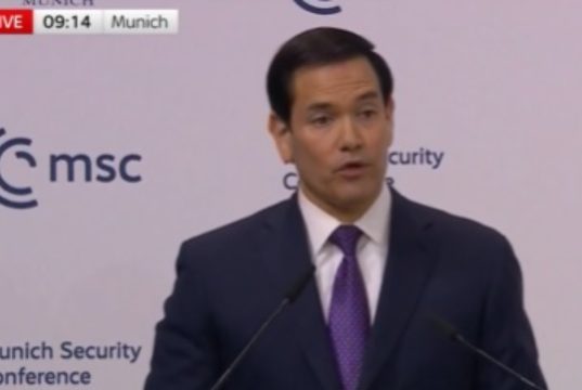 O secretário de Estado dos EUA, Marco Rubio, de roupa social, falando, sério, sem olhar para a câmera