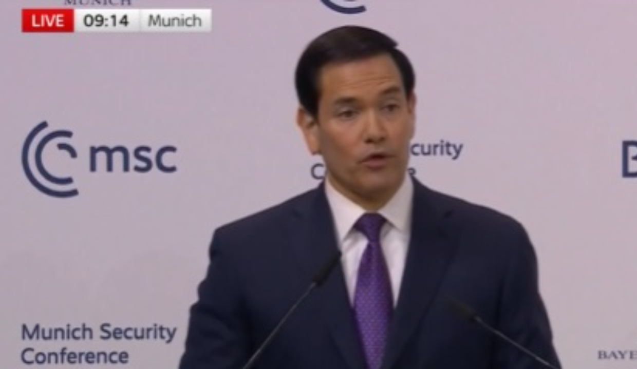 O secretário de Estado dos EUA, Marco Rubio, de roupa social, falando, sério, sem olhar para a câmera