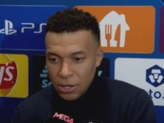 Kylian Mbappé falando, sério, sem olhar para a câmera, de roupa de frio escura