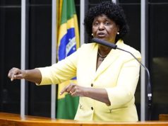 deputada federal Benedita da Silva (PT) de roupa amarela, falando em microfone, na Câmara, gesticulando