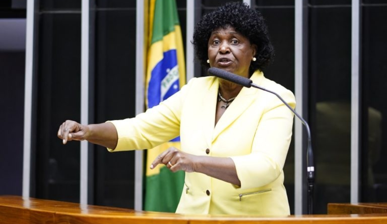 deputada federal Benedita da Silva (PT) de roupa amarela, falando em microfone, na Câmara, gesticulando