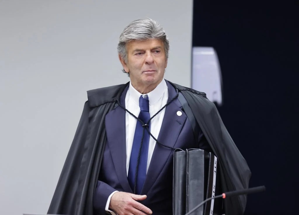 O ministro Luiz Fux sério, em pé, sem olhar para a câmera