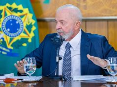 presidente Lula sentado, olhando para o lado, sério, falando