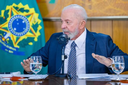 presidente Lula sentado, olhando para o lado, sério, falando