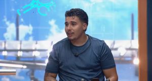 Pedro Henrique Espindola, do BBB 26, sério, olhando para o lado, de camiseta azul