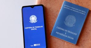 Celular com logo da Carteira de Trabalho e Carteira de Trabalho física