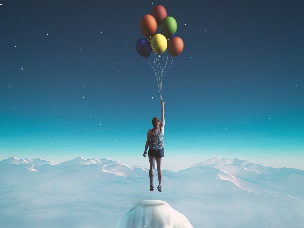 Menina sendo erguida por bexigas coloridas